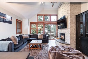 A living room with a sectional sofa, a coffee table, a fireplace, and a TV mounted on the wall. - Pet friendly | Hot tub | BBQ | Free parking (Whistler)