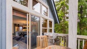 A modern house with a large sliding glass door leading to a dining area with a table and chairs. - Pet friendly | Hot tub | BBQ | Free parking (Whistler)