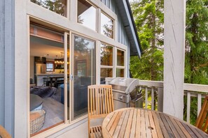 A modern house with a large sliding glass door leading to a dining area with a table and chairs. - Pet friendly | Hot tub | BBQ | Free parking (Whistler)