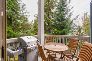 A covered outdoor area with a barbecue grill, wooden table, and chairs. - Pet friendly | Hot tub | BBQ | Free parking (Whistler)