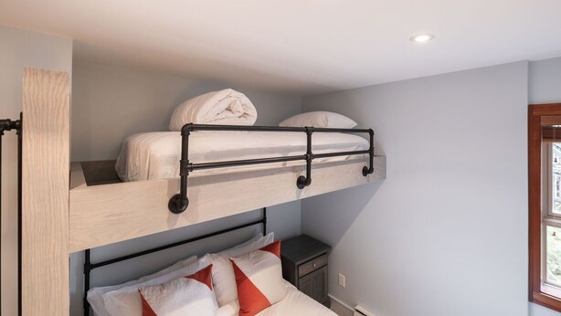 A bunk bed with a headboard, a small bedside table, and a window with daylight. - Pet friendly | Hot tub | BBQ | Free parking (Whistler)