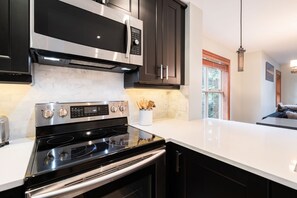 A modern kitchen with stainless steel appliances, dark cabinetry, and a white countertop. - Pet friendly | Hot tub | BBQ | Free parking (Whistler)