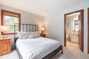 Una camera da letto con un letto, comodini, una finestra e vista sul bagno.