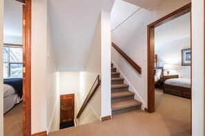 A bedroom with a bed, a nightstand, a lamp, and a window. - Large deck with BBQ | Hot Tub | Golf Course (Whistler)