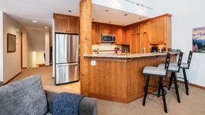 Eine moderne Küche mit Holzschränken, Edelstahlgeräten und einer Bar mit Hockern.