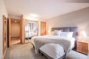 A bedroom with a bed, bedside tables, a wardrobe, and a mirror. - BBQ | Free Parking | Spacious | Forest views (Whistler)