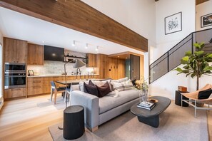 A modern living room with a sofa, coffee table, and a staircase. - Stunningly renovated | Walk to Blackcomb | Private Garage | Pets (Whistler)
