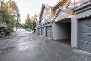 Una calle residencial con casas, un baño químico azul y el suelo cubierto de nieve.
