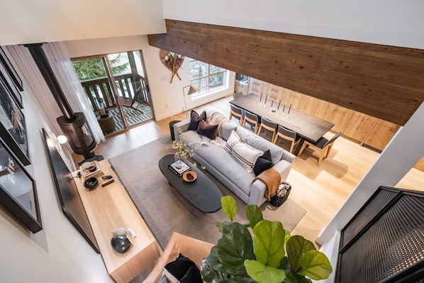 A modern living room with a grey sofa, wooden dining table, and large windows. - Stunningly renovated | Walk to Blackcomb | Private Garage | Pets (Whistler)