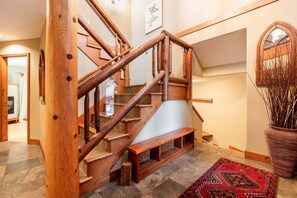 Eine Holztreppe mit Glastrennwand, einem gemusterten Teppich und einem dekorativen Spiegel.