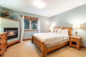 Ein Schlafzimmer mit Bett, Nachttisch, Lampe, Kommode und Kamin.