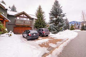 A two-story house with a garage, parked cars, and snow-covered trees. - Private hot tub | Private garage | BBQ | Luxury (Whistler)