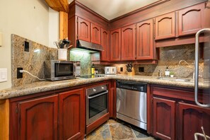 Eine Küche mit Granit-Arbeitsplatten, Edelstahlgeräten und Holzschränken.