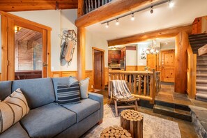 Ein gemütliches Wohnzimmer mit einer Couch, einer Holztreppe und einem Küchenbereich.