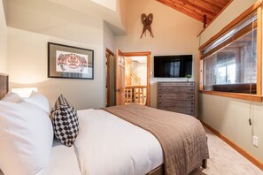 Ein Schlafzimmer mit Bett, Kommode, Fernseher und Fenster.