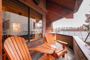 A wooden deck with Adirondack chairs and a table, overlooking a snowy landscape. - Amazing location | Private hot tub | Free parking (Whistler)