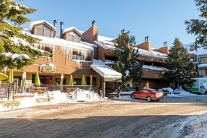 Ein Gebäude mit einem geneigten Dach, ein rotes Auto davor und Schnee auf dem Boden.