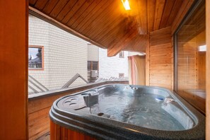 Eine Holzhütte mit Whirlpool, einem Fenster und einer Holzbalkendecke.