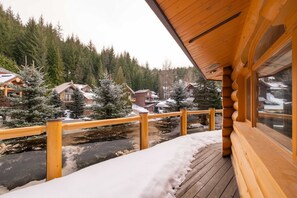 A wooden deck with a view of a snowy landscape and houses. - Luxury log chalet | Private hot tub | Ski-in/out (Whistler)