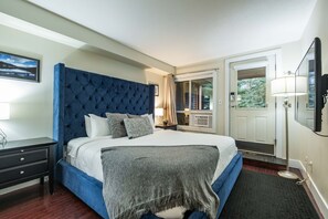 A bedroom with a large bed, a nightstand, a dresser, a window with curtains, a door, and a wall-mounted TV. - Excellent location | Private hot tub | Pets | BBQ (Whistler)