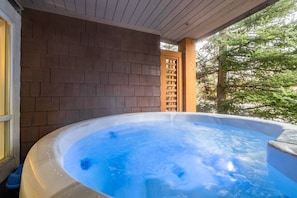 A hot tub on a porch with a brick wall and a wooden lattice. - Excellent location | Private hot tub | Pets | BBQ (Whistler)