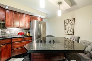 A kitchen with wooden cabinets, a stainless steel refrigerator, a red toaster, and a black countertop. - Excellent location | Private hot tub | Pets | BBQ (Whistler)
