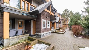 En boligbygning med en overdækket veranda, stenplantere og en murstenssti.