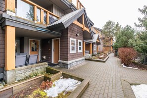 Ein Wohngebäude mit überdachter Veranda, Steinpflanzgefäßen und einem Ziegelweg.