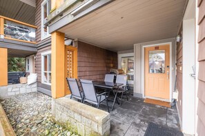 Eine überdachte Terrasse im Freien mit Tisch und Stühlen, einer Steinmauer und einer Holztür mit der Nummer 23.