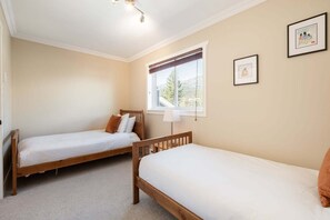 A bedroom with two wooden beds, a window with a view, and a lamp. - Private Bike Storage | Free parking | Mountain Views | Window AC (Whistler)
