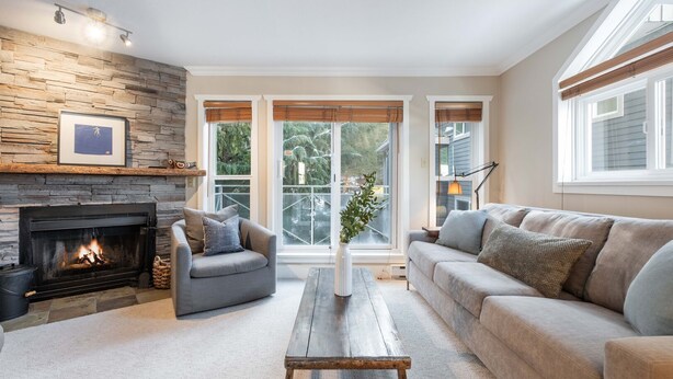 A living room with a fireplace, a sofa, a chair, and a coffee table. - Private Bike Storage | Free parking | Mountain Views | Window AC (Whistler)