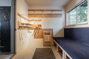 A compact room with a bed, a wooden bench, a coat rack, and a window. - Private Bike Storage | Free parking | Mountain Views | Window AC (Whistler)