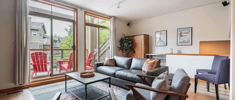 En moderne stue med sofa, stole, sofabord og udsigt til det fri.