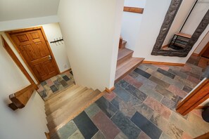 Un escalier avec des marches en bois et un sol en pierre disposé en motif de chevrons.