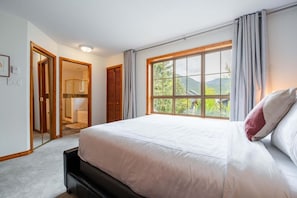 Ein Schlafzimmer mit einem großen Bett, einem Fenster mit Blick auf Grünflächen und einem begehbaren Kleiderschrank.