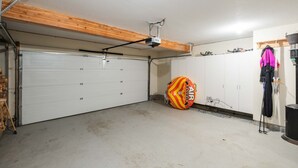 Uma garagem com porta branca, um ventilador de teto e uma fritadeira elétrica colorida no chão.