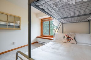 Ein Schlafzimmer mit Etagenbett, einem Fenster mit Blick auf Bäume und einer Decke mit Rasterstruktur.