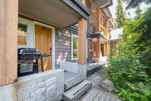 A wooden house with a porch, a grill, and a mailbox. - Private hot tub | Pets | BBQ | Location! (Whistler)