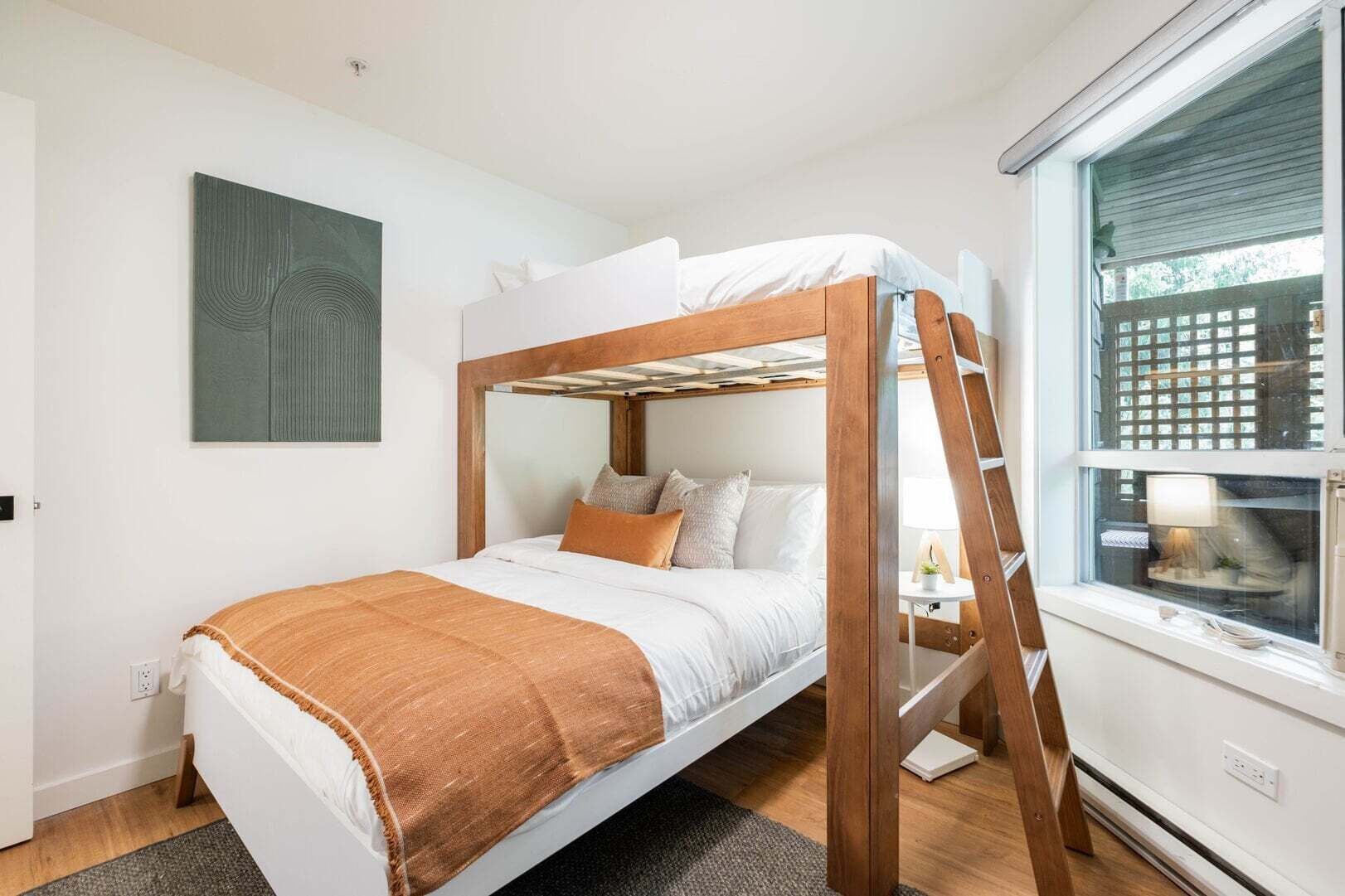 A bunk bed with a wooden frame, white bedding, and a brown throw blanket.