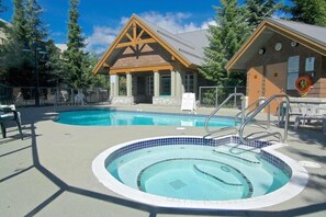 Ett poolområde med ett bubbelbad, en träbyggnad med ett triangulärt tak och en skylt.