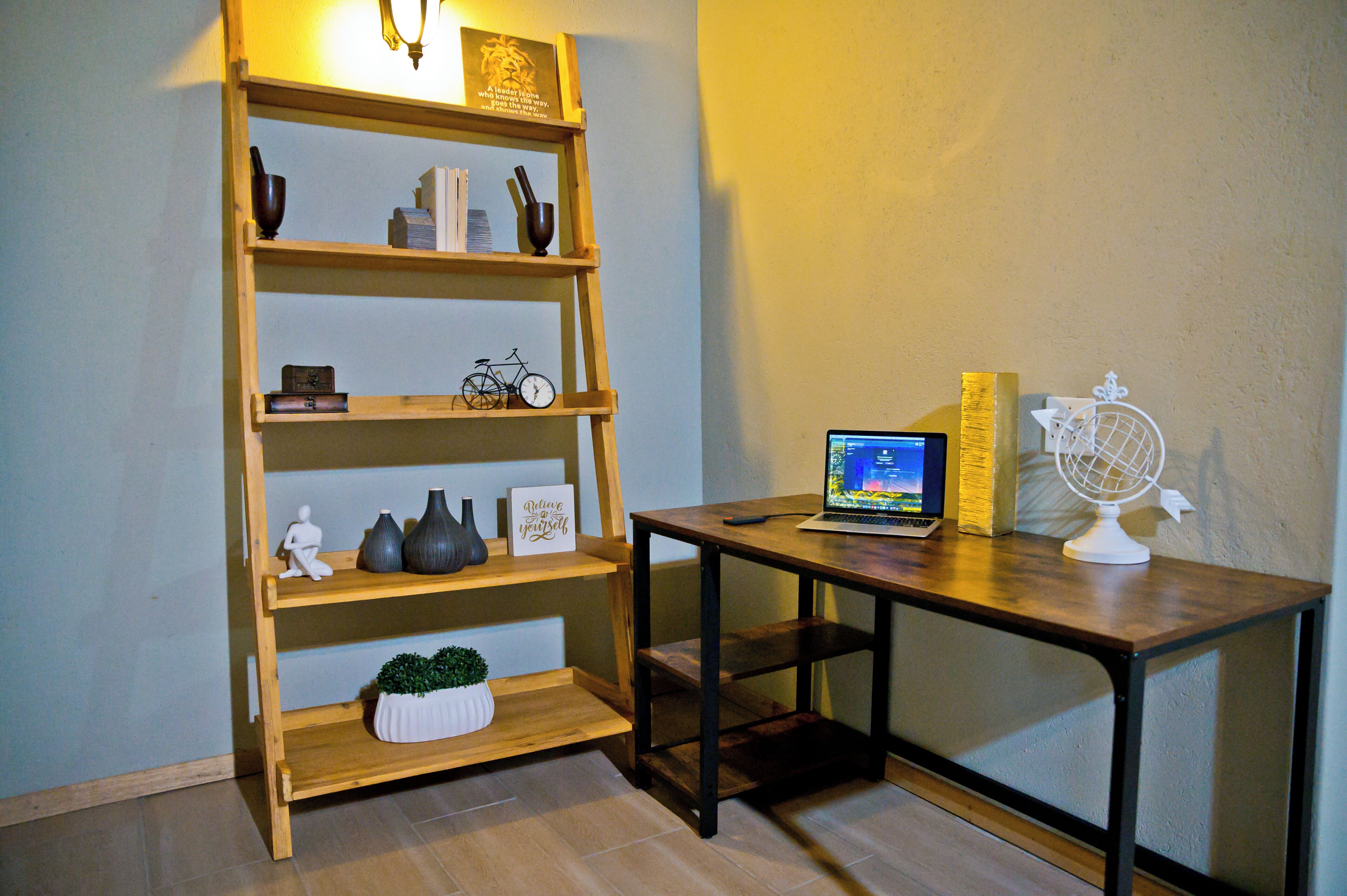A wooden bookshelf with various decorative items, a laptop on a table, and a globe.