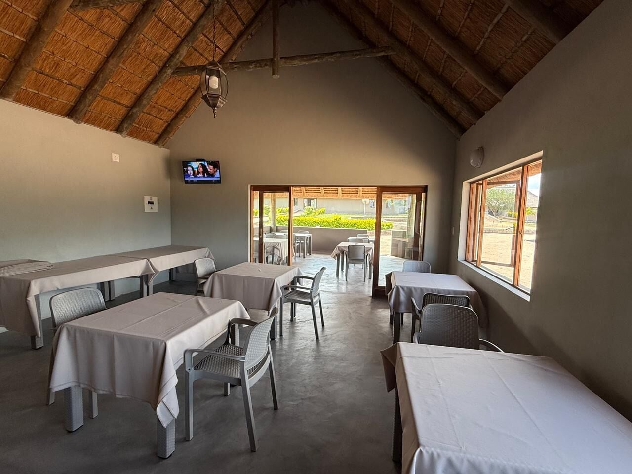 A restaurant with tables and chairs, a television, and large windows.