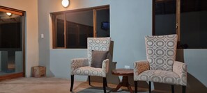 A room with two patterned armchairs, a small wooden table, and a window with a view.