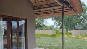 A building with a thatched roof, large glass doors, and a paved patio area.