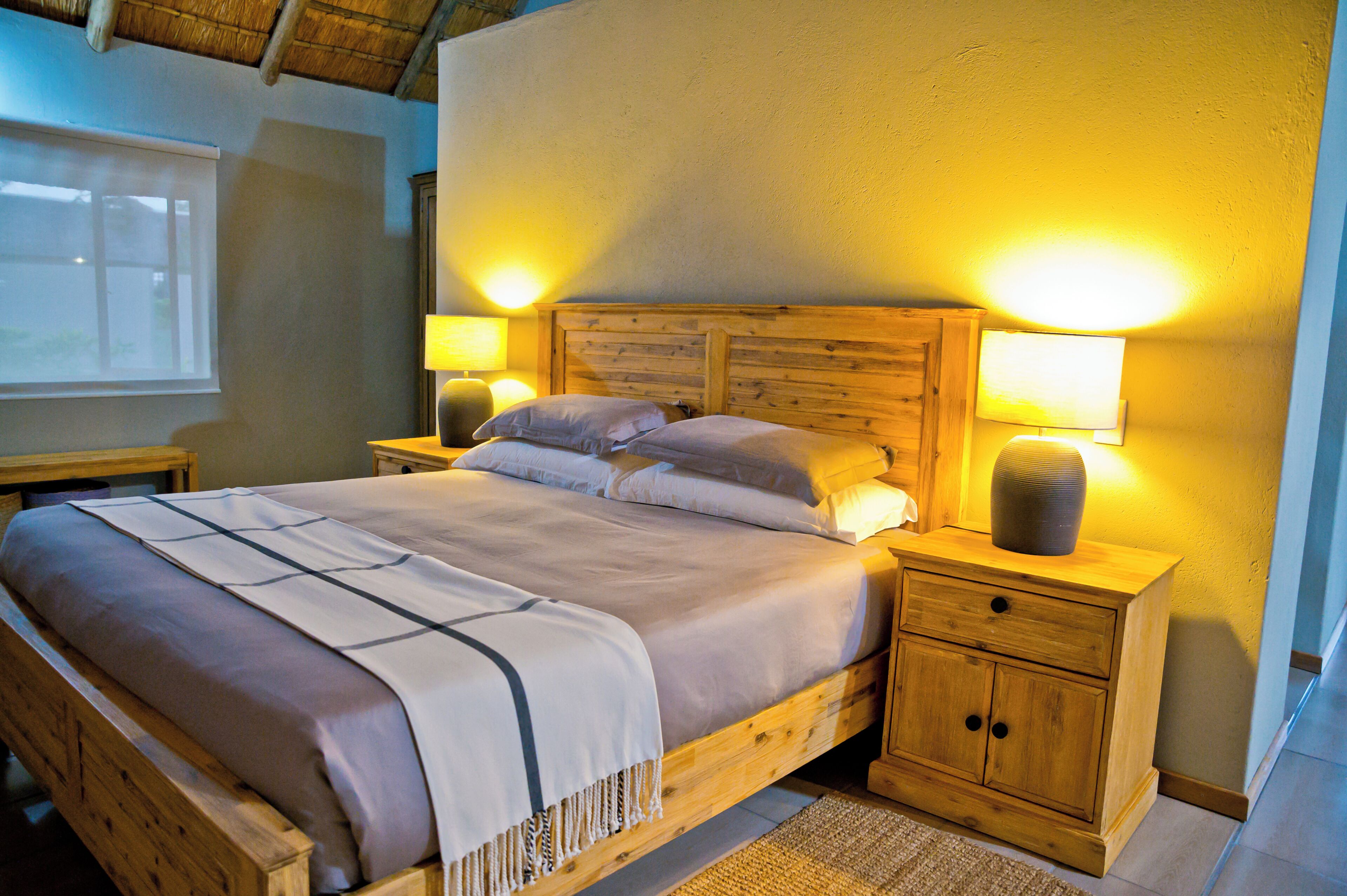 A wooden bed with a headboard, two bedside tables, and a nightstand with a lamp.