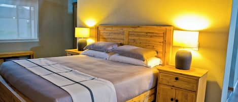 A wooden bed with a headboard, two bedside tables, and a nightstand with a lamp.