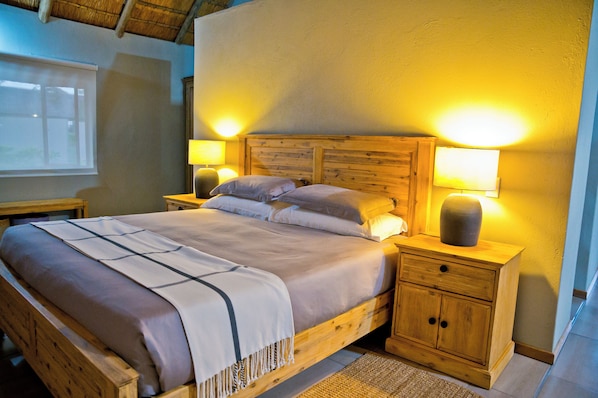 A wooden bed with a headboard, two bedside tables, and a nightstand with a lamp.