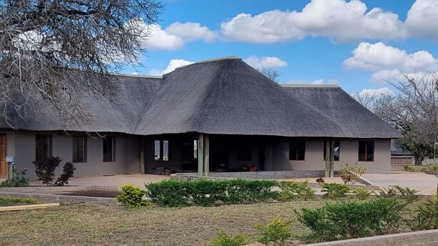A building with a unique thatched roof, a front porch, and a landscaped garden.