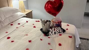 Un lit recouvert de pétales de rose, un ballon en forme de cœur, un seau à champagne et une pancarte sur laquelle on peut lire « M. et Mme ».