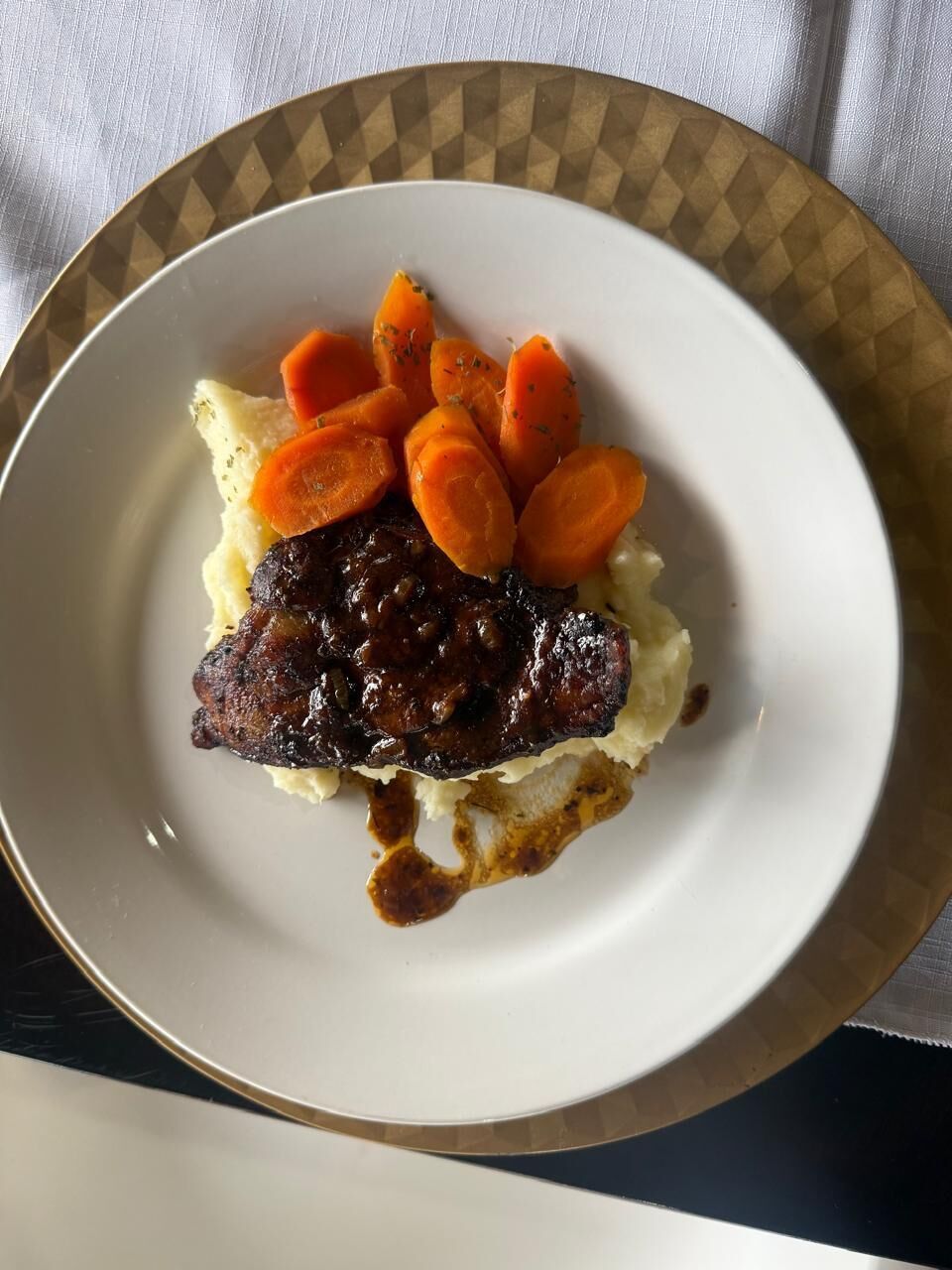 Un plato con carne, puré de papas y zanahorias en rodajas.